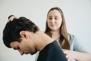 Licensed physical therapist guiding a patient through neck exercises during a concussion physical therapy session in a clinic.