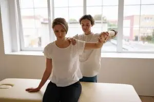 Physical therapist gently performing manual lymphatic drainage on a patient's arm in a clinic